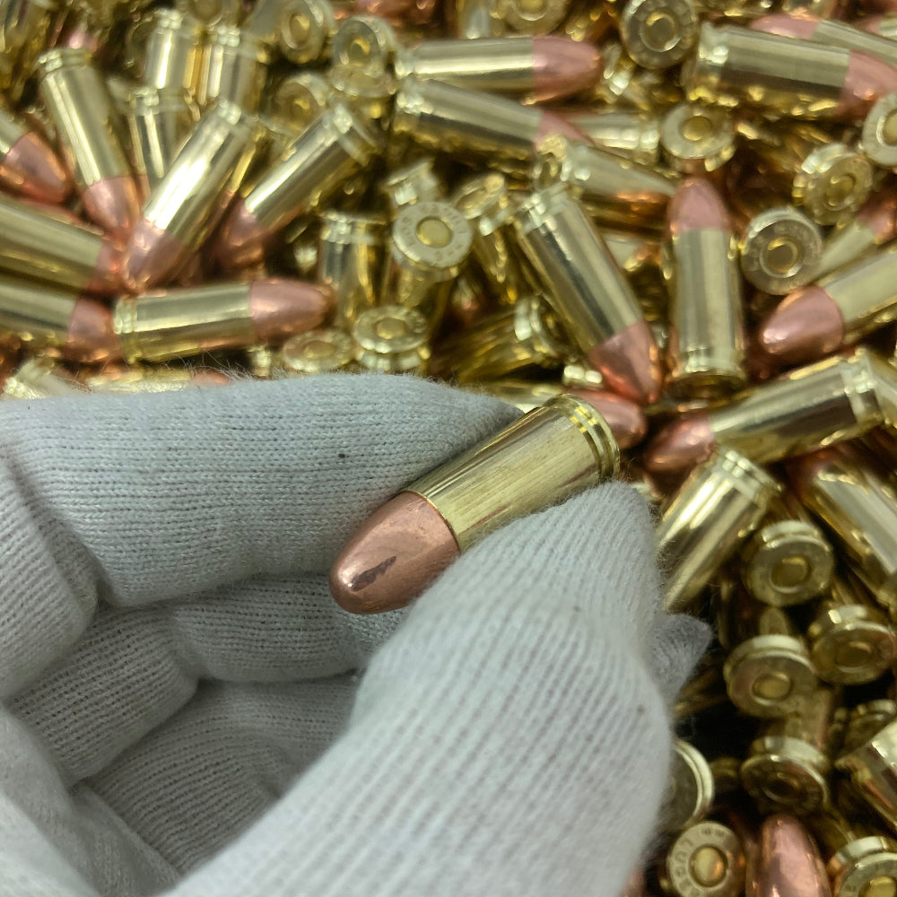 Hand holding a bullet amidst a pile of ammunition