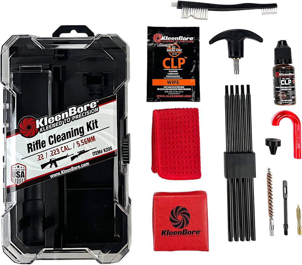 KleenBore Rifle Cleaning Kit shown in a clear plastic case with multiple included cleaning tools and accessories arranged beside it on a white background, including brushes, a black cleaning rod set, a red cloth, a red pouch, a bottle, wipes, and other cleaning accessories.